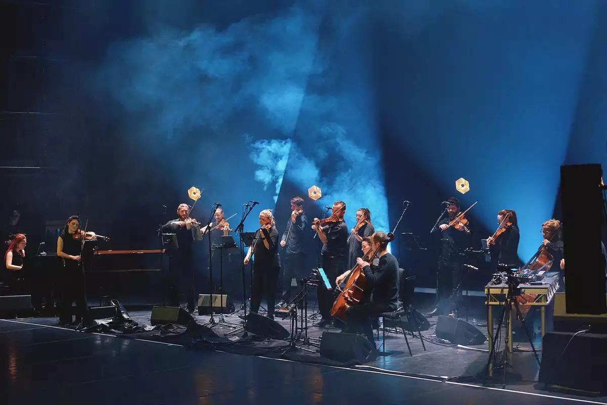 Manchester Collective performing on a stage with blue lighting