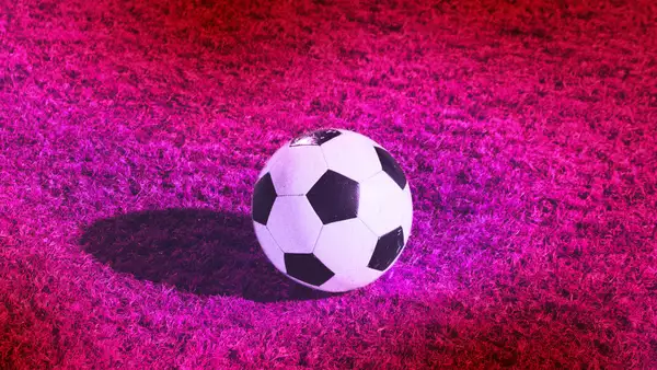 A football on a bright pink football pitch