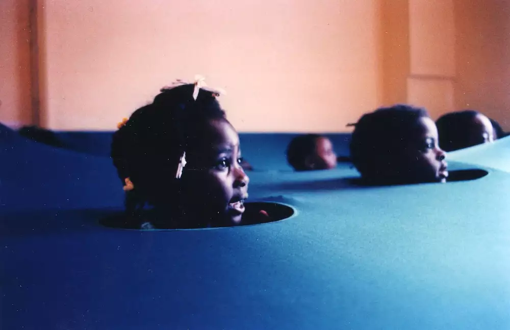 Children pop their heads out of holes in the ground