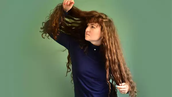 Artist Iora Holding her long curly hair up and peeking through it