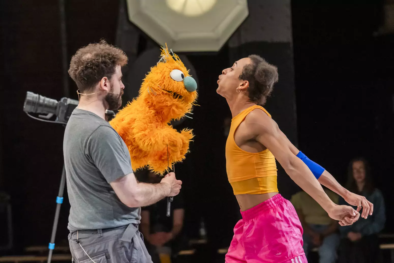 Two people on stage with an orange puppet performing